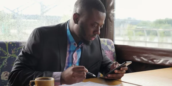 black-guy-is-making-paperwork-afro-american-businessman-is-filling-documets-summer-tent-cafe-looking-smartphone-writing-papers-hot-cup-coffee-table-he-wears-shirt-suit-jacket_255755-1168